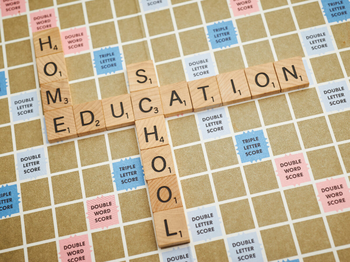 Wooden letter tiles spelling out home, education, and school on a game board