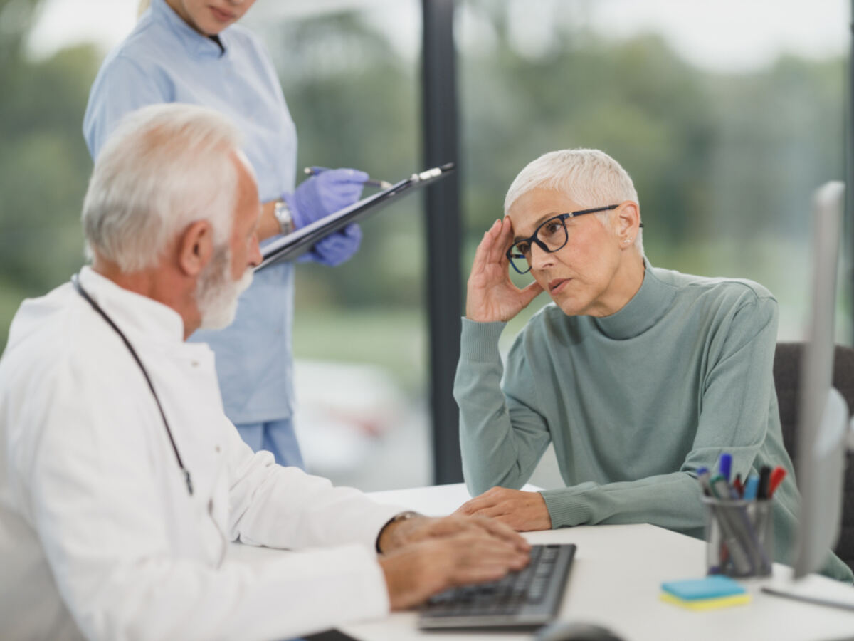 A doctor reviewing a chart with a patient at a clinic desk