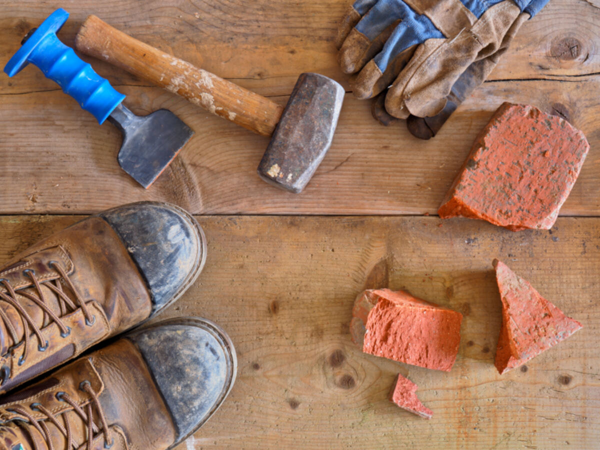 Work boots, gloves, and hand tools laid out on a wooden workbench