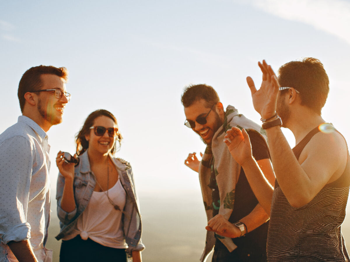 A group of friends laughing together outdoors at sunset
