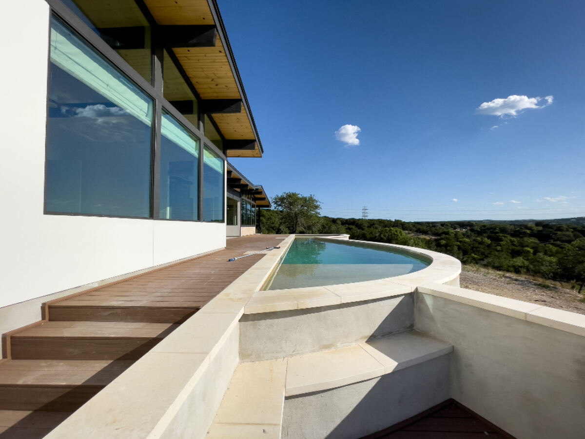 A modern house exterior with a private pool under a clear blue sky